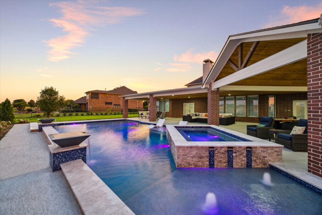 Custom pool and spa with fire bowls and covered patio at dusk, Greater Houston